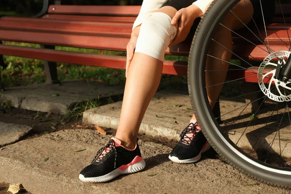 Γυναίκα Τραυματισμένο Γόνατο Ξύλινο Πάγκο Κοντά Στο Ποδήλατο Εξωτερικούς Χώρους — Φωτογραφία Αρχείου