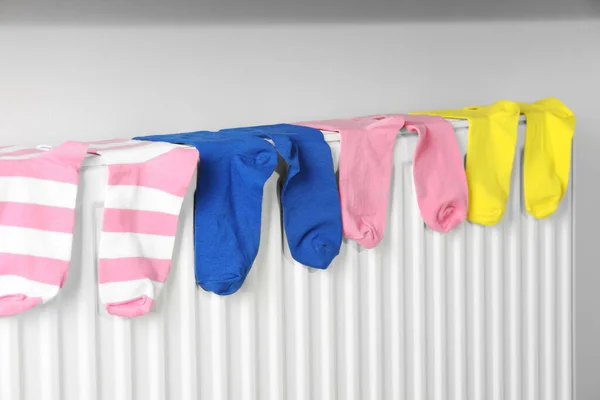 Beyaz Duvarın Yanındaki Isıtma Kaloriferinde Farklı Renkte Çoraplar — Stok fotoğraf
