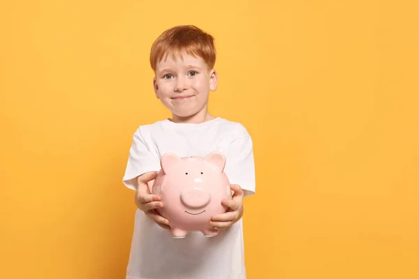 Netter Kleiner Junge Mit Keramik Sparschwein Auf Orangefarbenem Hintergrund — Stockfoto