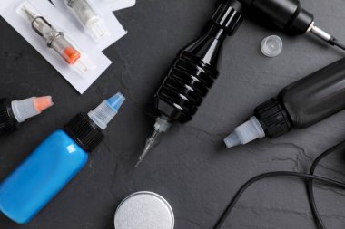 Siyah masanın üzerinde dövme malzemesi olan düz bir kompozisyon.