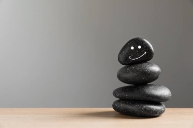 Açık gri arkaplan üzerinde çizilmiş mutlu yüzlü taşlar yığını, metin için boşluk. Zen kavramı