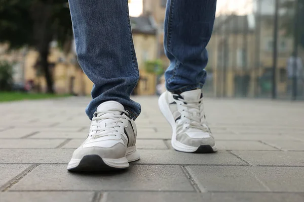 stock image Man in jeans and sneakers walking on city street, closeup