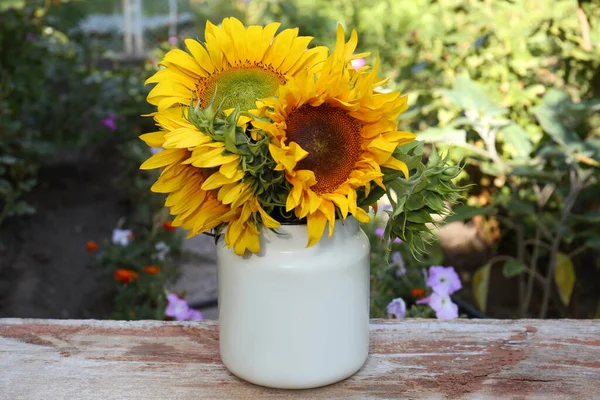 户外木制桌子上的铁罐里有一束美丽的向日葵 — 图库照片