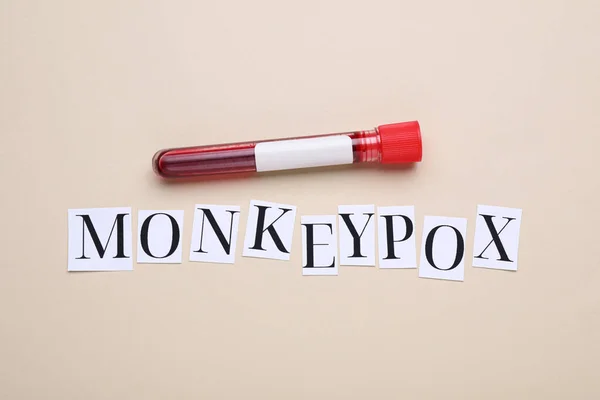 stock image Word Monkeypox and test tube with blood sample on beige background, flat lay