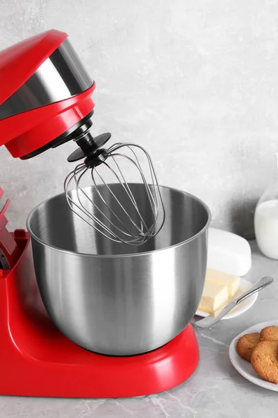 Modern red stand mixer, cookies and butter on light gray marble table