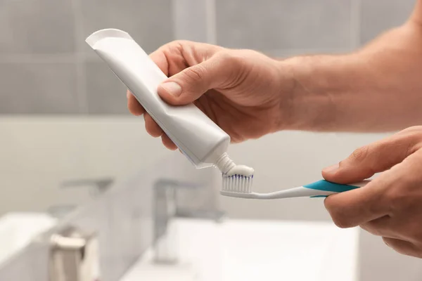 男子在浴室的刷子上涂牙膏 — 图库照片