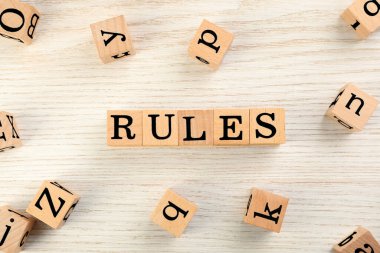 Word Rules made of cubes with letters on light wooden table, flat lay