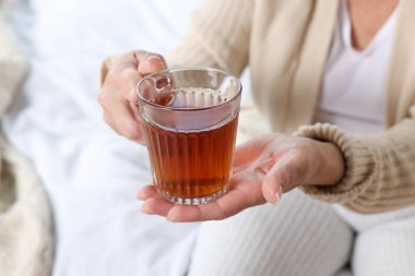 Elderly woman with cup of hot tea indoors, closeup. Home care service