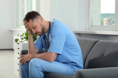 Hastanede kanepede oturan bitkin doktor.