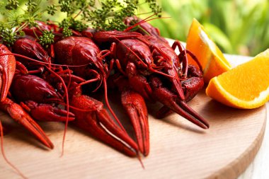 Lezzetli kırmızı kaynatılmış kerevit ve portakal tahtada, yakın plan.