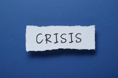 Mavi arkaplanda kelime krizi olan kağıt parçası, üst görünüm