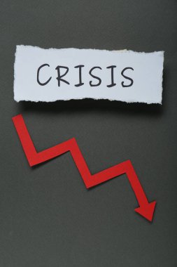 Kağıt parçası kelime krizi ve alçalan kırmızı ok siyah arka planda, düz yatıyordu