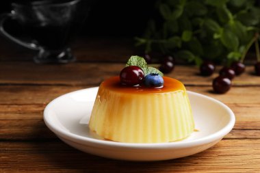 Ahşap masada yaban mersinli, kirazlı ve nane aromalı lezzetli karamel pudingi.