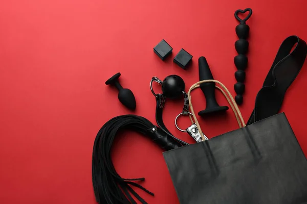 stock image Shopping bag and different sex toys on red background, flat lay. Space for text