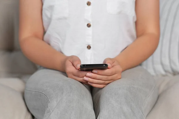 自宅のソファでスマートフォンを使用している女性 クローズアップ — ストック写真