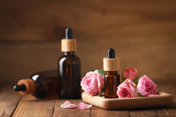 Flaschen Mit Ätherischem Rosenöl Und Blumen Auf Dem Holztisch — Stockfoto