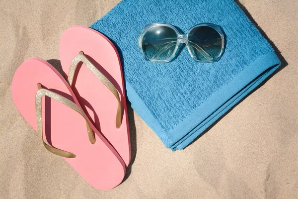 柔らかい青のビーチタオルにフリップフロップとサングラスを砂の上に折り フラットレイ — ストック写真