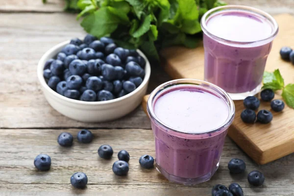 stock image Freshly made blueberry smoothie on wooden table, space for text