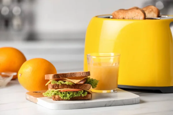 黄色烤面包机 烤面包片 三明治 橙子和果汁放在白色大理石桌上 — 图库照片