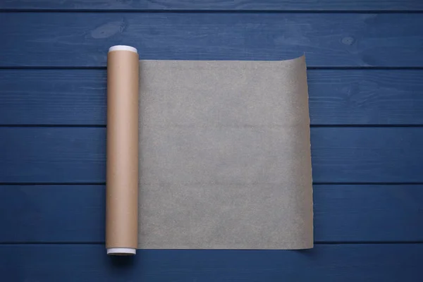 青い木製のテーブルの上に紙を焼くのロール トップビュー — ストック写真