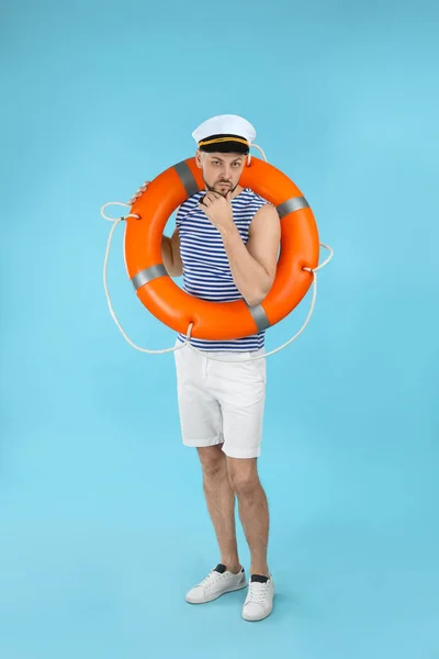 Sailor with orange ring buoy on light blue background