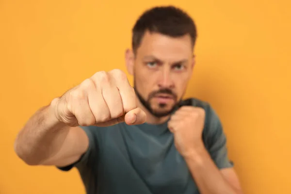 Man Throwing Punch Orange Background Focus Fist Space Text — Stock Photo, Image