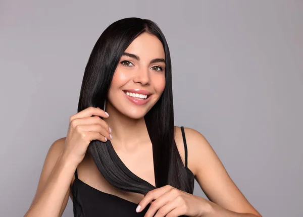 明るい灰色の背景に健康な強い髪を持つ美しい若い女性の肖像画 — ストック写真