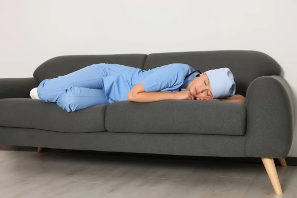 stock image Tired young doctor sleeping on sofa indoors