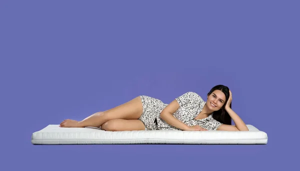 Young Woman Lying Soft Mattress Light Purple Background — Stock Photo, Image