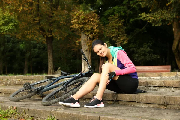 Mujer Joven Con Rodilla Lesionada Escalones Cerca Bicicleta Aire Libre —  Fotos de Stock