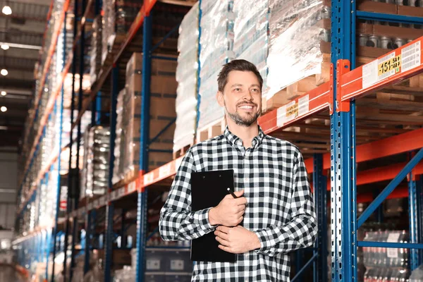 stock image Happy manager holding clipboard in warehouse with lots of products, low angle view