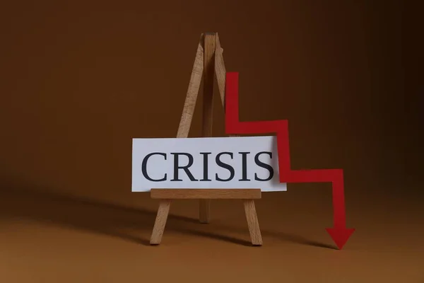 危機と茶色の背景に赤い矢印を降順言葉で木製のイーゼル — ストック写真