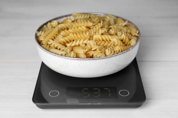 stock image Electronic scales with uncooked pasta on white wooden table