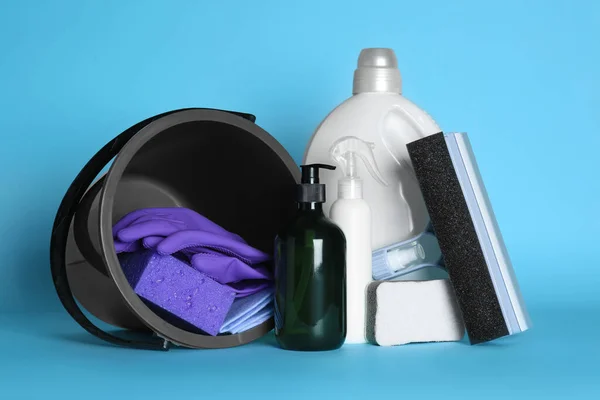 Black bucket, cleaning supplies and tools on light blue background