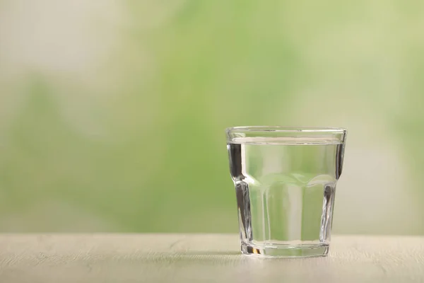 stock image Glass of pure water on white wooden table against blurred background, space for text