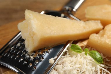 Grated parmesan cheese with basil near grater, closeup