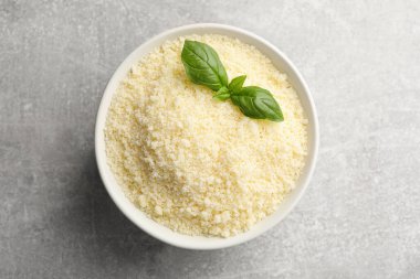 Gri masada rendelenmiş parmesan peynirli ve fesleğenli kase.