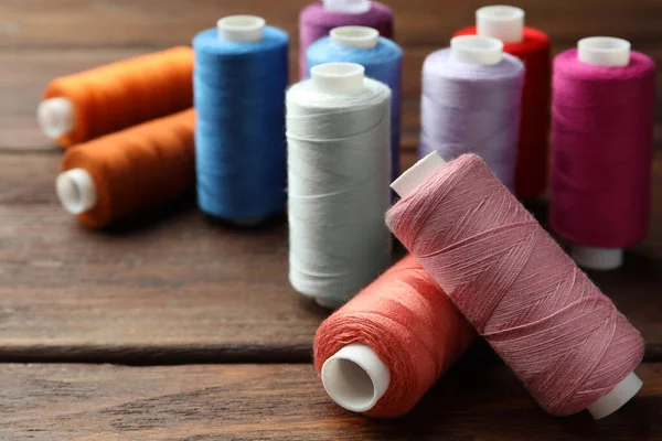 stock image Different colorful sewing threads on wooden table, closeup. Space for text