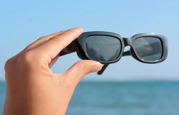 stock image Woman holding stylish sunglasses near sea, closeup