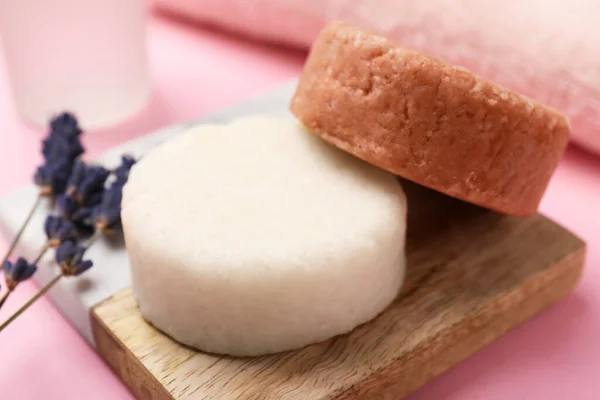 Solid shampoo bars and lavender on pink table, closeup. Hair care