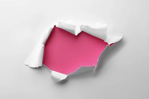 stock image Hole in white paper on pink background