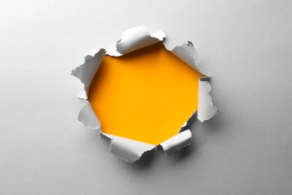 Stock image Hole in white paper on yellow background