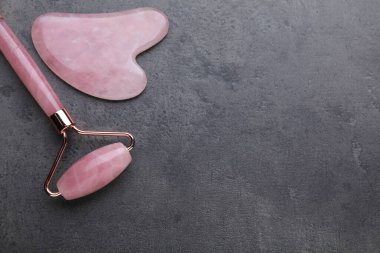 Quartz gua sha aracı ve gri arka planda yüz silindiri düz yatıyordu. Metin için boşluk