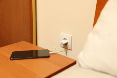 Modern smartphone charging from electric socket indoors