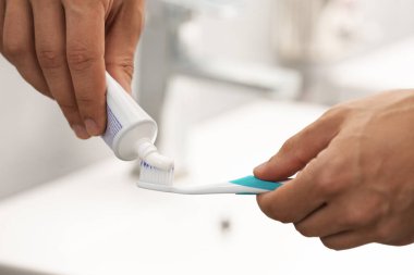 Banyoda diş fırçasına diş macunu süren adam, yakın plan.