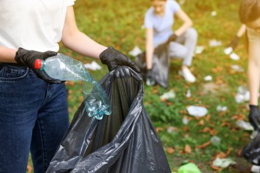 Plastik çantalı kadın parkta çöp topluyor, yakın plan.