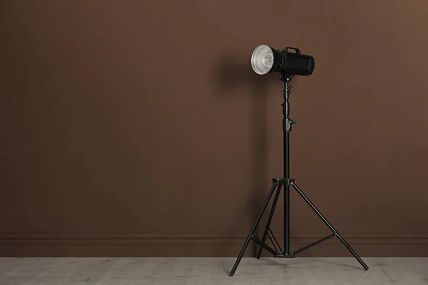 工作室闪光灯与反射镜在三脚架靠近棕色墙壁的房间 空间为文字 专业摄影师设备 — 图库照片