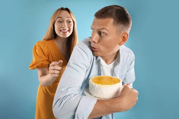 Greedy Man Hiding Tasty Cake Woman Turquoise Background — Stock Photo, Image
