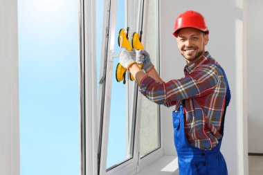 Worker using suction lifters during plastic window installation indoors