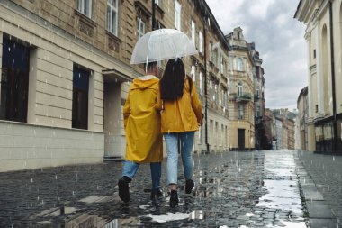 Şemsiyeli genç ve güzel bir çift yağmur altında yürüyorlar.